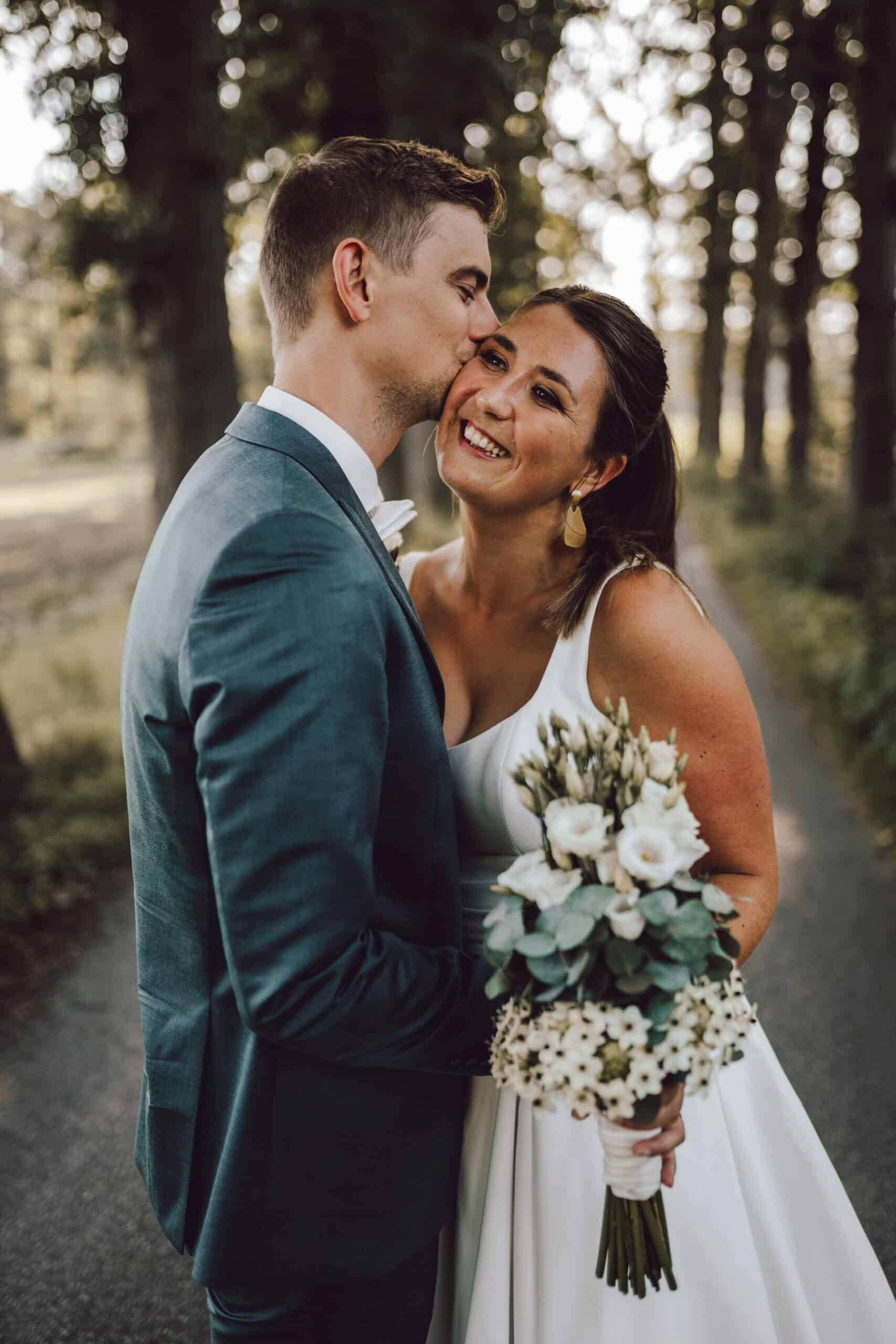 Hochzeitsfotograf Osnabrück - Brautpaar in einer Allee küsst sich