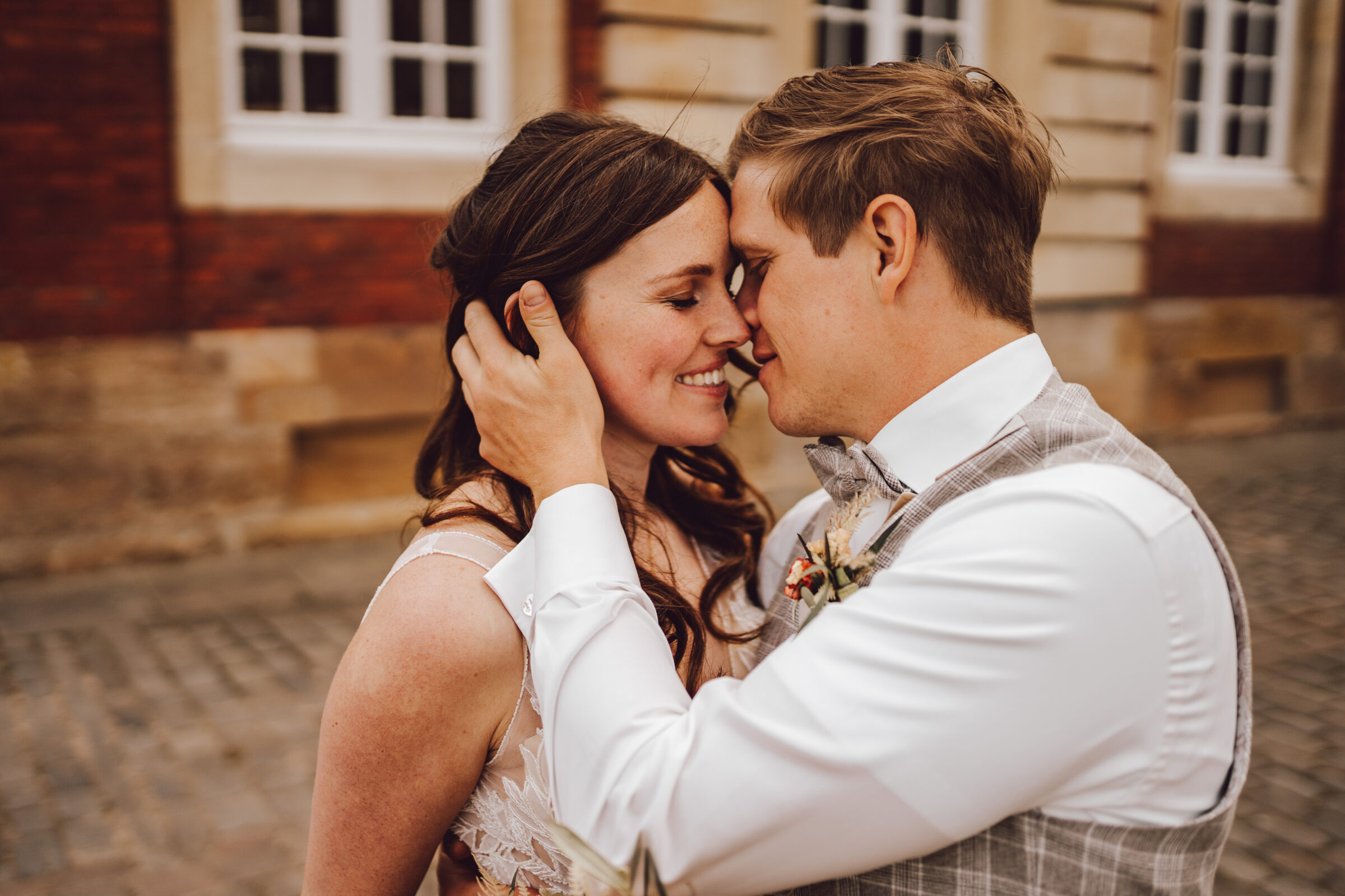 Brautpaar küsst sich vor einem Gebäude